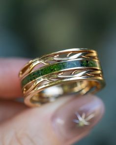 a hand holding a gold and green ring