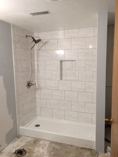 a bathroom that is being remodeled with tile on the floor and shower head in place