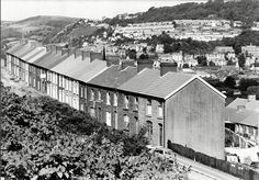 an old black and white photo of houses in the hills above town with mountains in the background