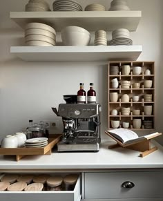 a coffee maker sitting on top of a kitchen counter next to plates and mugs