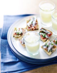 a plate topped with small pieces of food next to two glasses of milk on top of a table