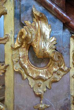 an ornate gold mirror mounted to the side of a building with wood trimmings