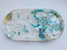 a piece of glass with blue and yellow paint on the bottom, sitting on a white surface