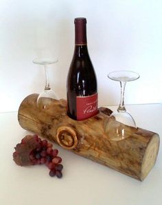 a bottle of wine sitting on top of a piece of wood next to two glasses