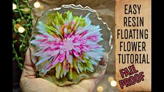 a person holding a flower in their hand with the words easy resinin floating flower tutorial