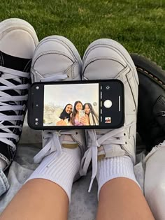 someone taking a selfie with their cell phone in front of two pairs of shoes