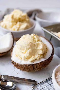 two coconuts with whipped cream in them on a white surface next to spoons