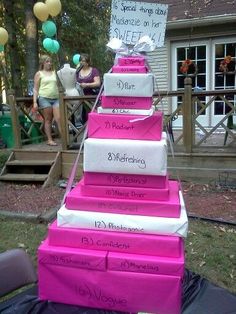 a stack of pink boxes sitting on top of a table next to a woman standing in front of a house