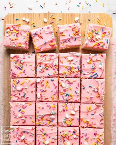 pink frosted cake with sprinkles on a cutting board