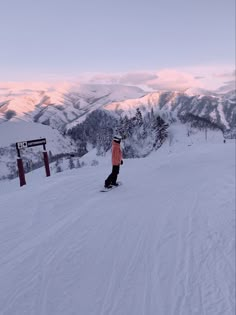 a person riding a snowboard on top of a snow covered slope with mountains in the background