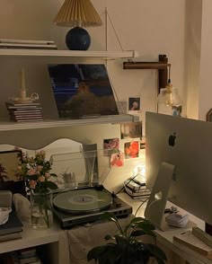 an apple computer sitting on top of a desk next to a plant in a vase