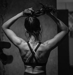 the back of a woman with her hands on her head, in black and white