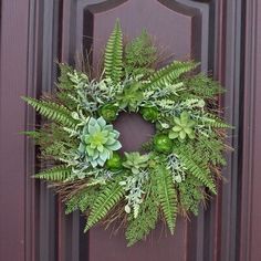 a green wreath on a door with succulents