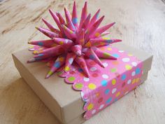 a pink gift box sitting on top of a wooden table with polka dot paper around it