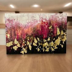 a painting on a wooden table in a room with white and gold paint splattered over it