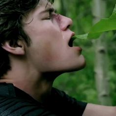 a young man with his mouth open while eating leaves