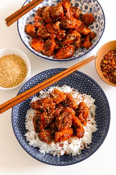 two plates filled with rice and meat next to chopsticks on a white table