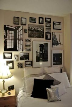 a white bed topped with lots of pictures on the wall next to a night stand