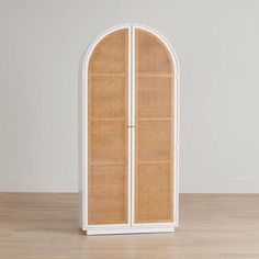 a white and brown wicker cabinet sitting on top of a hard wood floor next to a wall