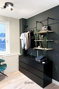 an empty room with clothes hanging on the rack, and a chair in front of it