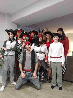 a group of people in pirate costumes posing for a photo with one man wearing a hat