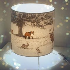 a lamp shade with an image of animals on it and a tree in the background