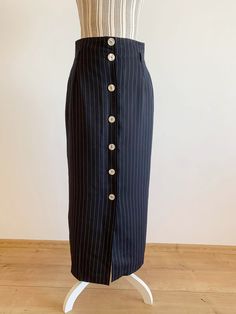 "This is a beautiful vintage black maxi skirt with delicate white vertical stripes for slimming effect and button front closure. This longline skirt is made of polyester fabric with acetate lining underneath. This minimalist skirt has an elegant timeless straight cut silhouette with high waistline and belt loops. This black maxi skirt is perfect for the office, business or casual attire. It was made in Italy. The size marked is Italy 48, which fits like size M. Please check the measurements belo Fitted High Waist Skirt With Side Buttons, Pinstripe Vertical Stripes Skirt For Work, Chic Long Striped Skirt, Striped Long Flowy Skirt, Skirt Office Wear, Fitted Black Skirt With Vertical Stripes, Black And White Striped Maxi Skirt, Striped Maxi Skirts, Black Maxi Skirt