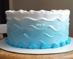 a blue and white frosted cake sitting on top of a wooden table