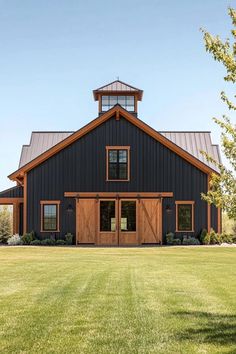 a large black barn with wooden doors and windows