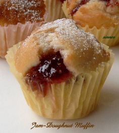 three muffins with powdered sugar and jam on them sitting on a white surface