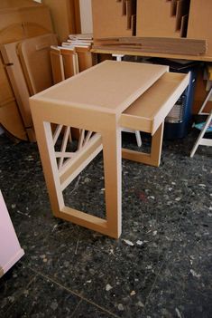 a table that is sitting in the middle of a room with some boxes behind it