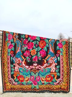 a large colorful tapestry hanging on the side of a building