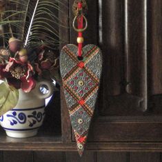 a vase filled with flowers sitting on top of a wooden shelf next to a potted plant