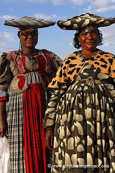 two women dressed in traditional african dress and headgear, standing next to each other