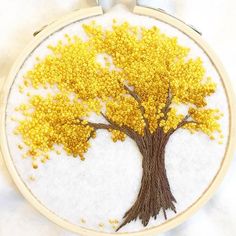 a yellow and brown tree embroidered onto a white fabric