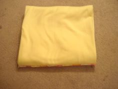 a piece of yellow cloth sitting on top of a carpeted floor next to a wall