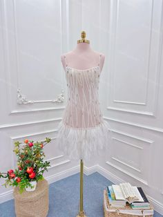 a mannequin with a dress on display next to a flower pot and books