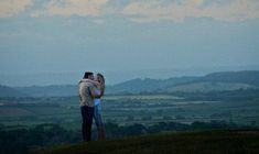 two people embracing each other on top of a hill