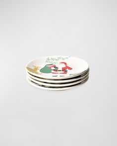 four plates with christmas designs on them sitting side by side in front of a white background