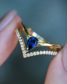 a close up of a person's hand holding a ring with a blue stone