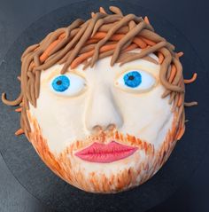 a cake that has been decorated to look like a man's face with hair and blue eyes