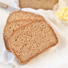 three slices of bread sitting on top of a white table cloth next to butter and a knife