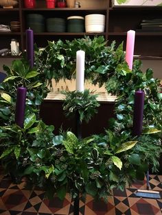 a wreath with candles and greenery is on display in front of a book shelf