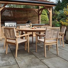 an outdoor dining table and chairs with grill in the backgroung area next to it