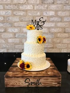 a wedding cake with sunflowers and mr and mrs topper sitting on a table