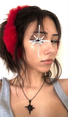 a woman with a cross painted on her face is wearing a red feather headband