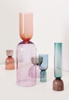 several different colored vases sitting on top of a white table next to each other