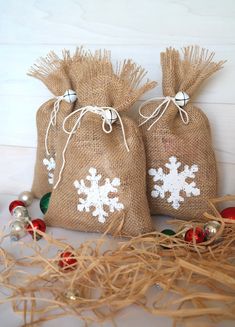 two burlap bags with snowflakes on them sitting next to christmas ornaments