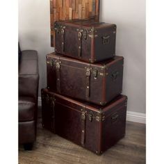 three suitcases stacked on top of each other in front of a chair and wall