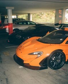 an orange sports car is parked in a parking garage next to other cars on the street